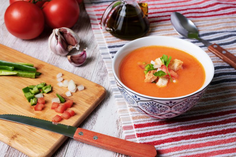 Gazpacho, cold soup typical of Andalusia based on tomato, garlic, pepper and onion. On a white wooden background.