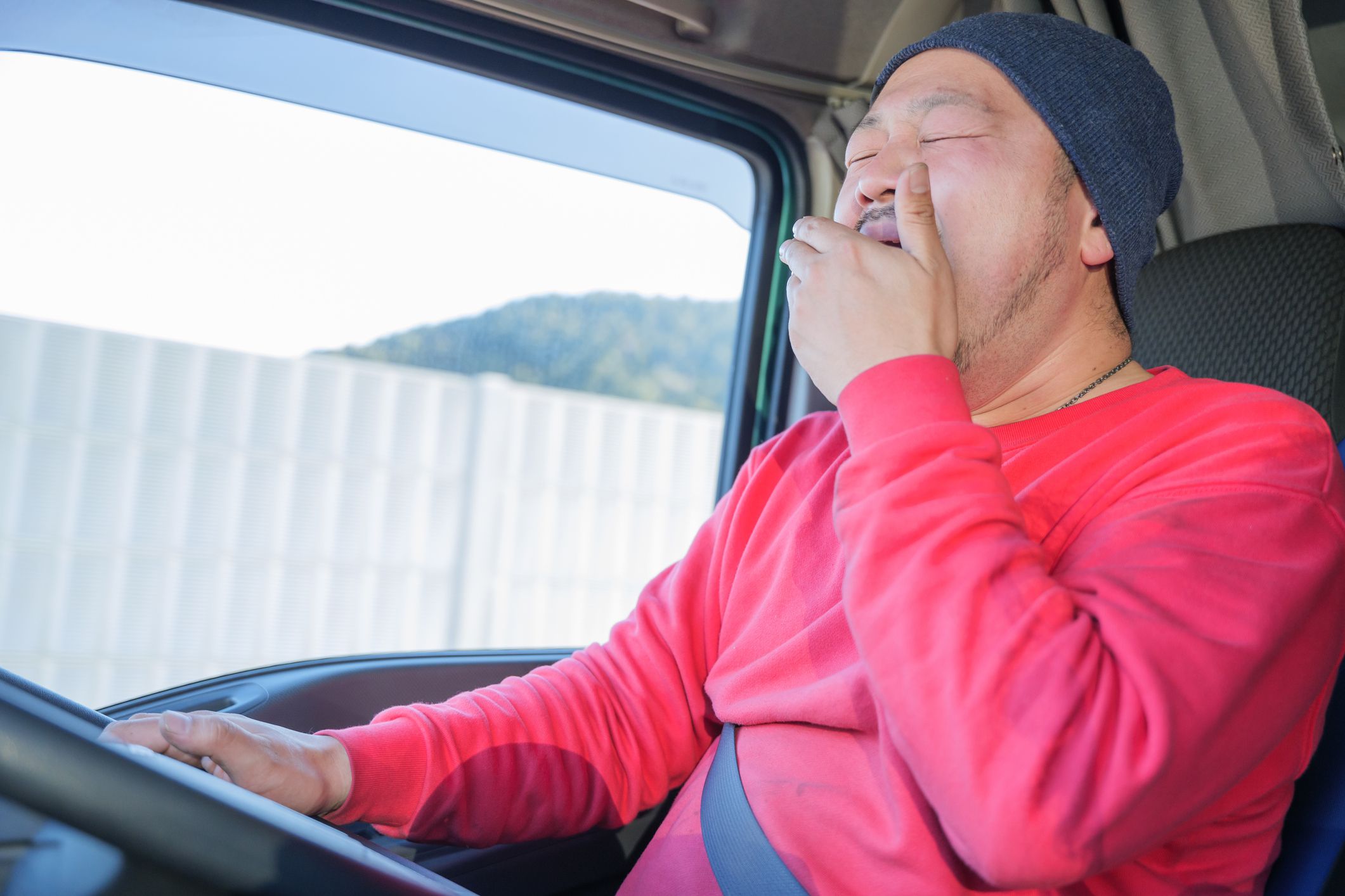 Male driver driving heavy truck while yawning