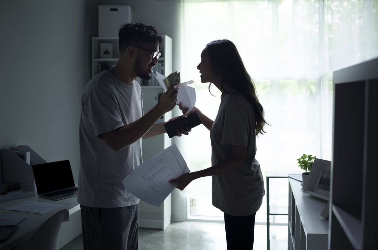 A couple arguing in a dark-lit kitchen area.