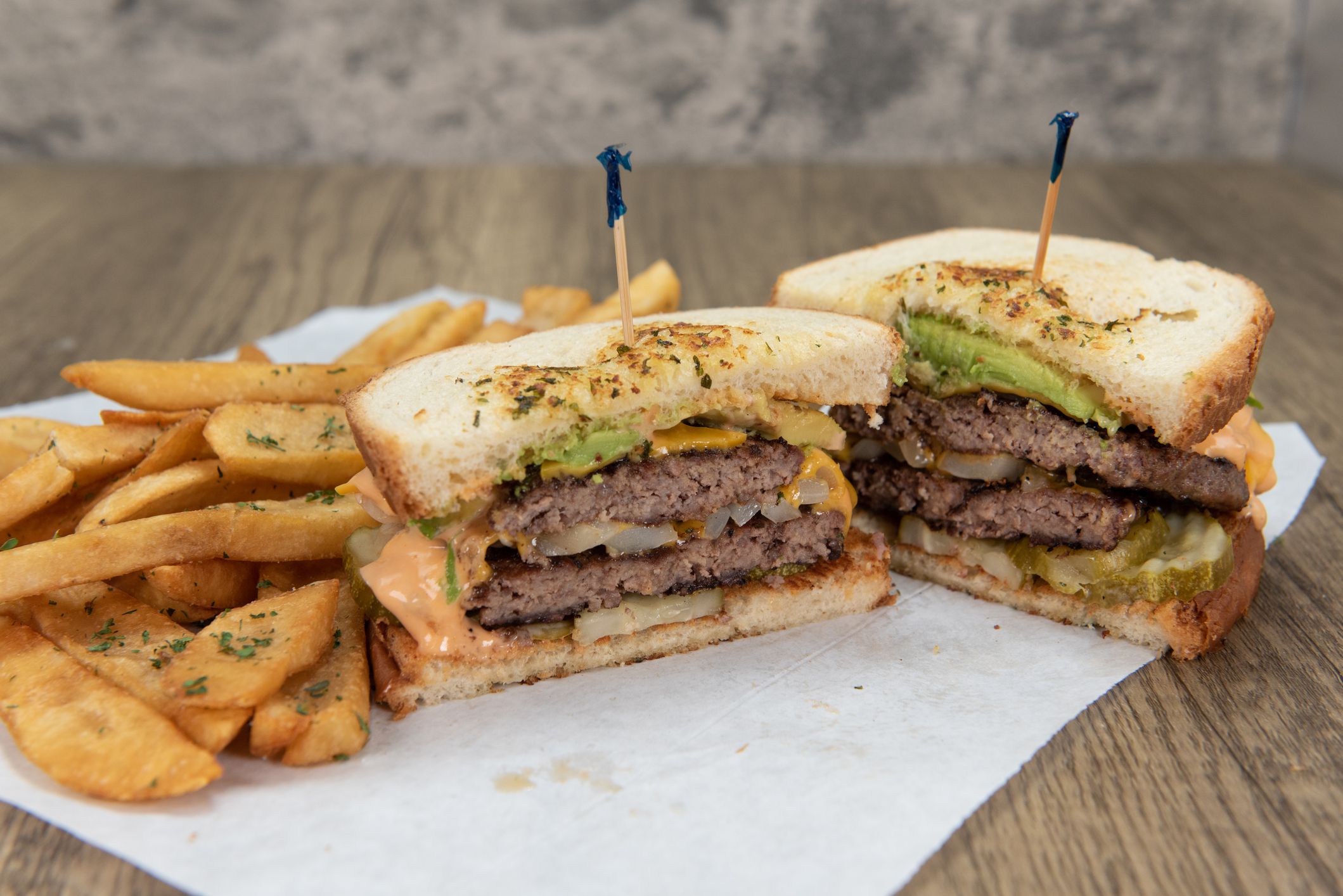 Double decker patty melt sandwich with double hamburger on sour dough bread with pepper steak fries for a party appetite hunger meal.