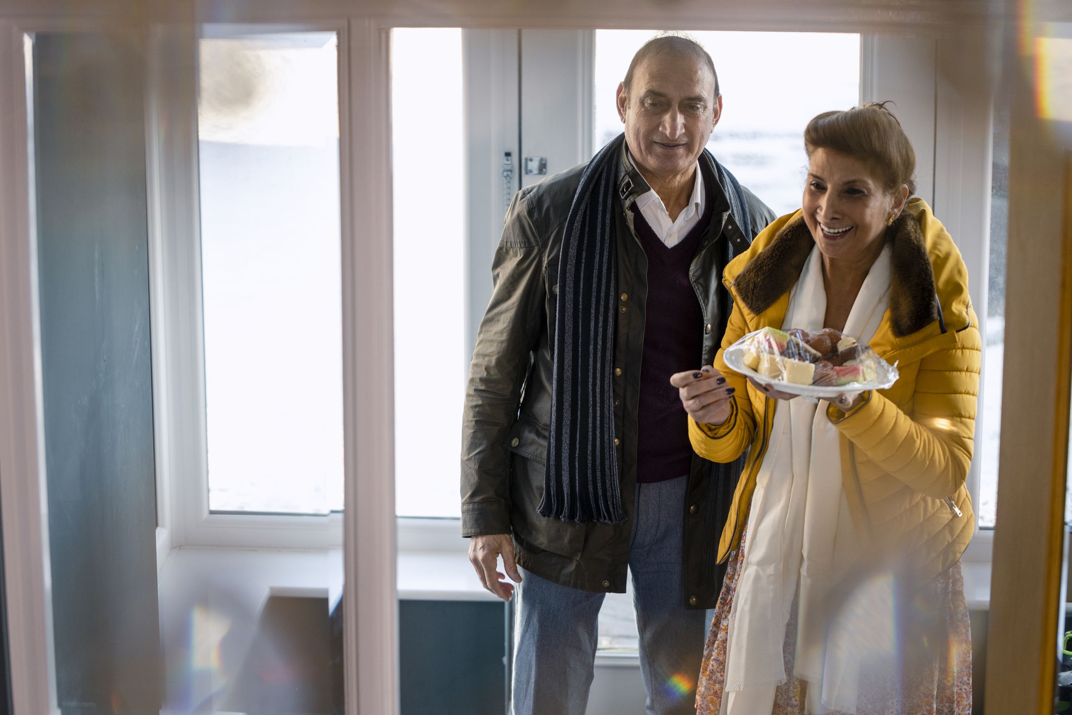A medium wide angle view of two grandparents entering their daughters family home in the North East of England. They have arrived with deserts for them to have at their family Diwali celebrations.