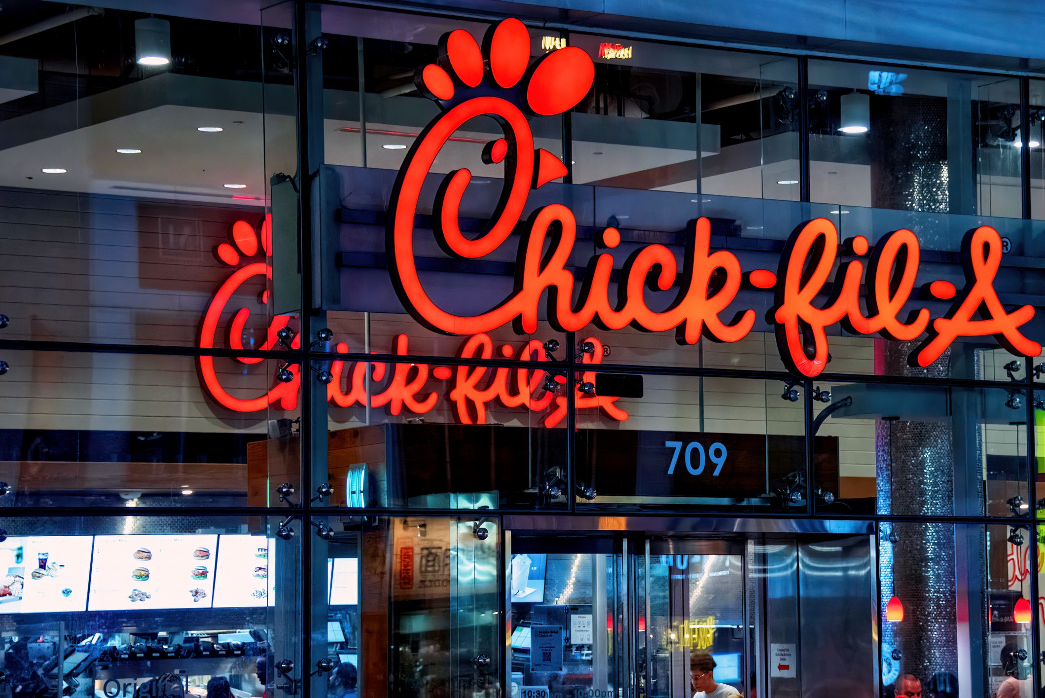 Toronto, Canada - August 8, 2022: Chick-fil-A at Bloor and Yonge with sign on the outside and inside visible. The American fast-food restaurant chain specializes in chicken sandwiches.