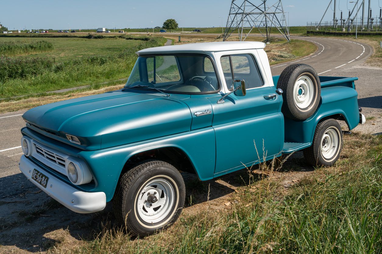 A nice blue vintage truck parked beside a farm field.