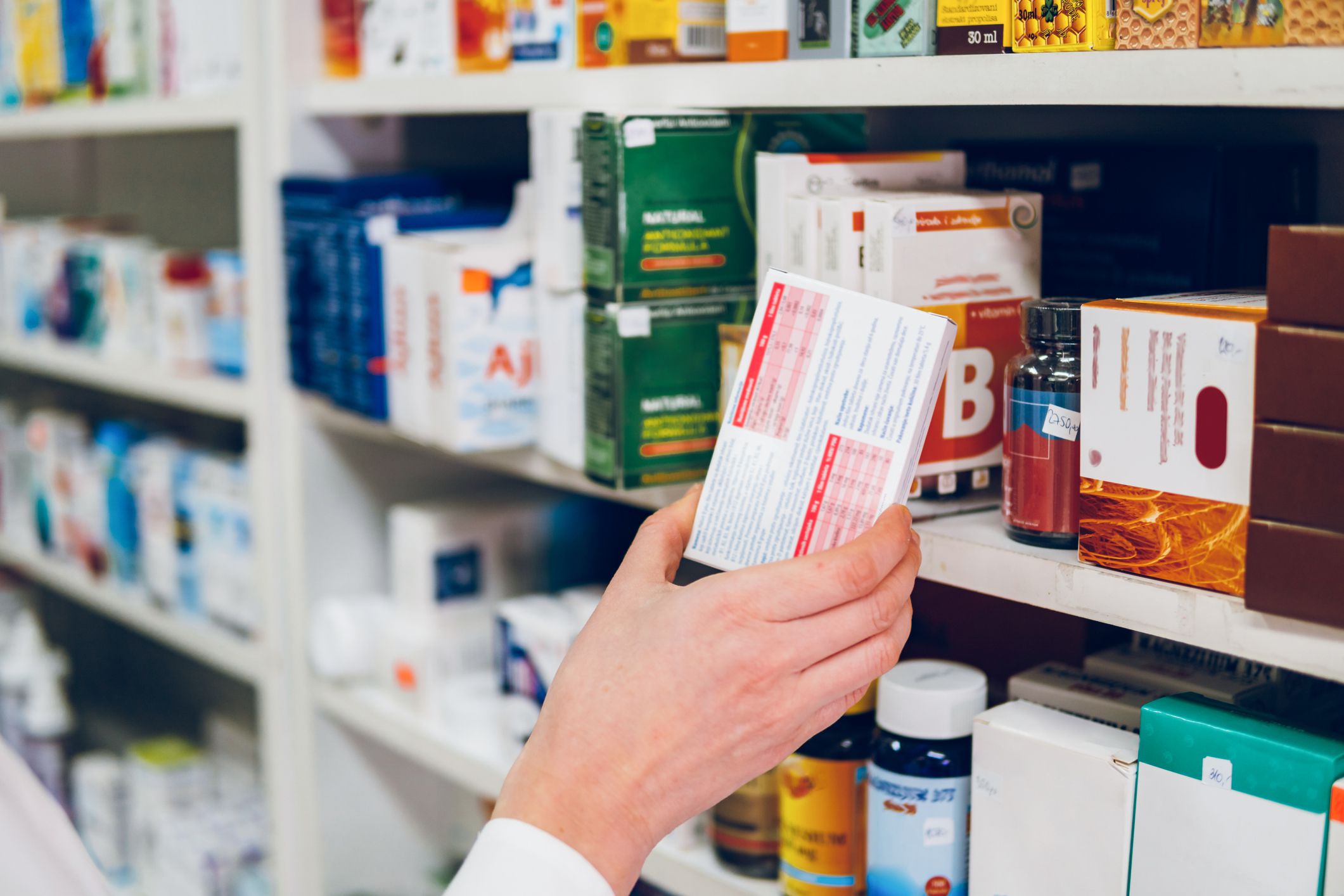 A young female pharmacist arranges medicines on the shelves of the pharmacy and makes an inventory.