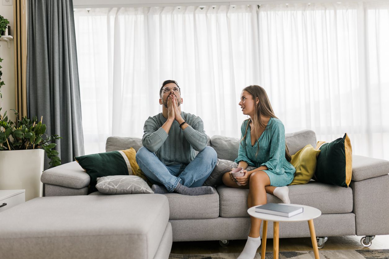 A couple arguing while they sit on the couch.