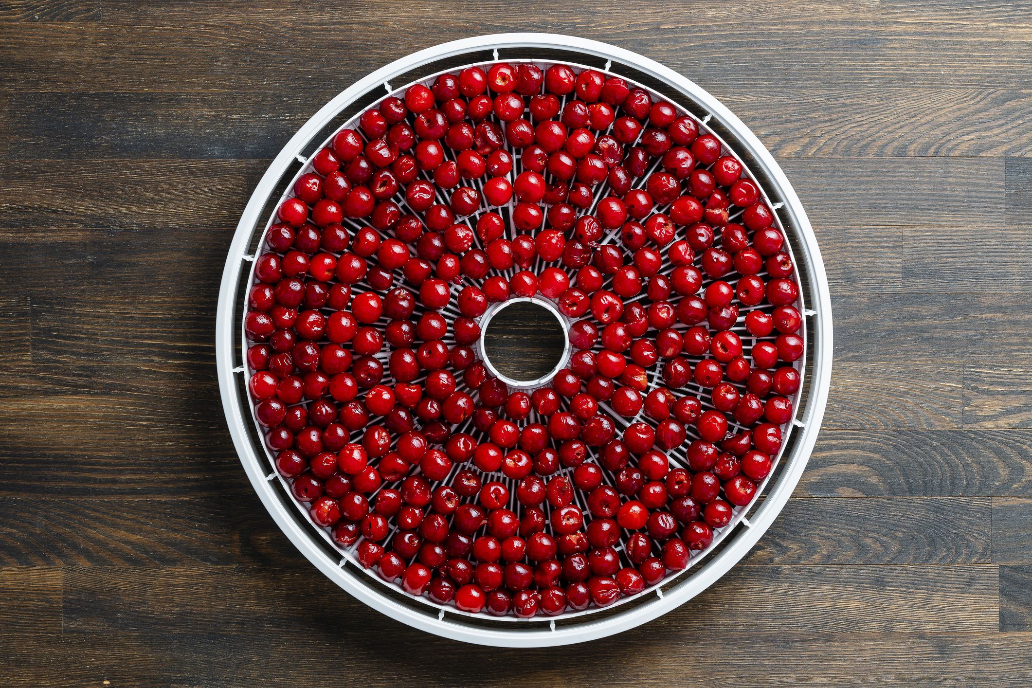 Prepared ripe red pitted cherries on a drying tray for dehydrator, close up, top view. A way to preserve vitamins. Vegetarian meal, healthy and useful