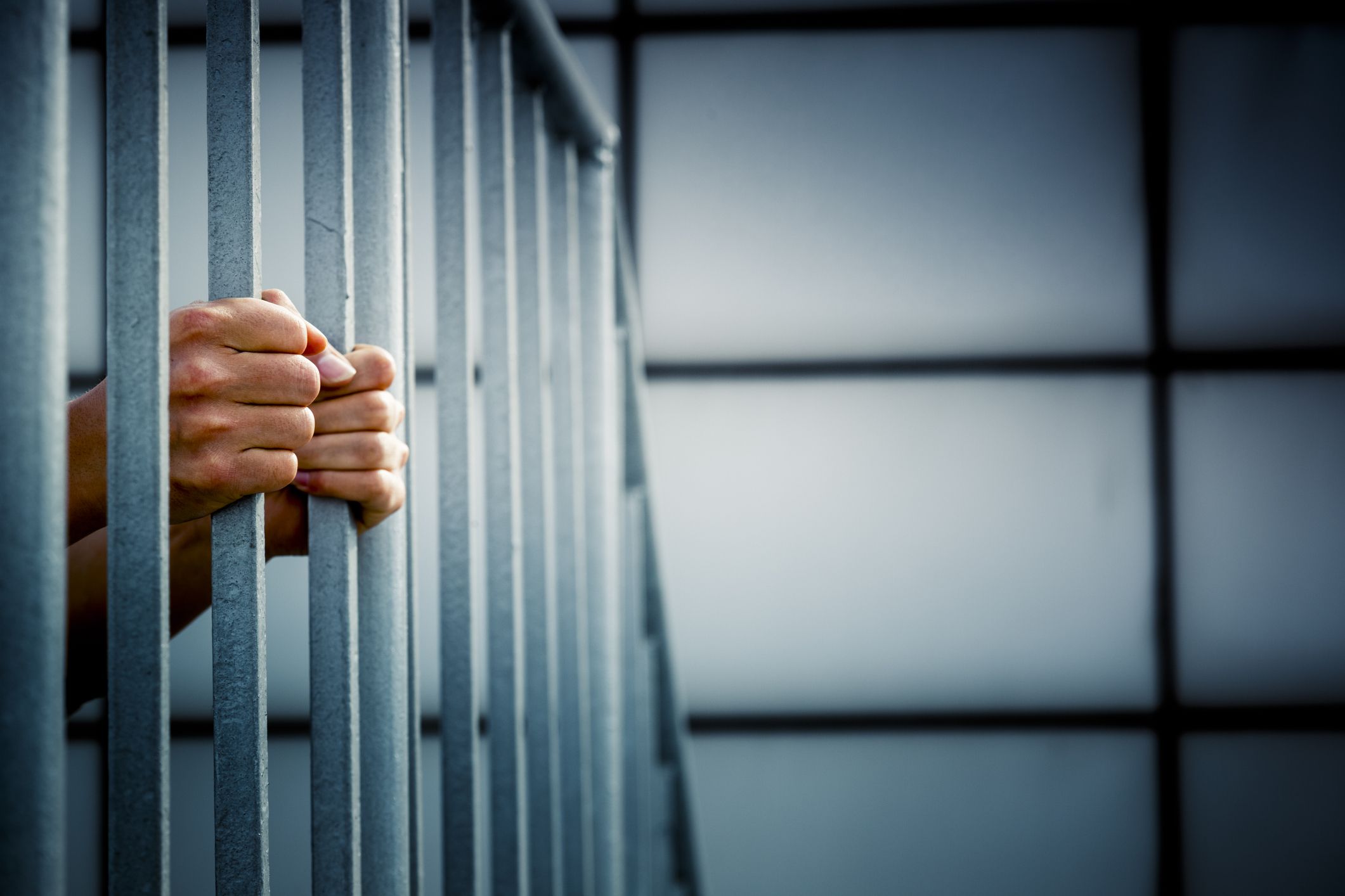 A prisoner behind the jail cell bars .