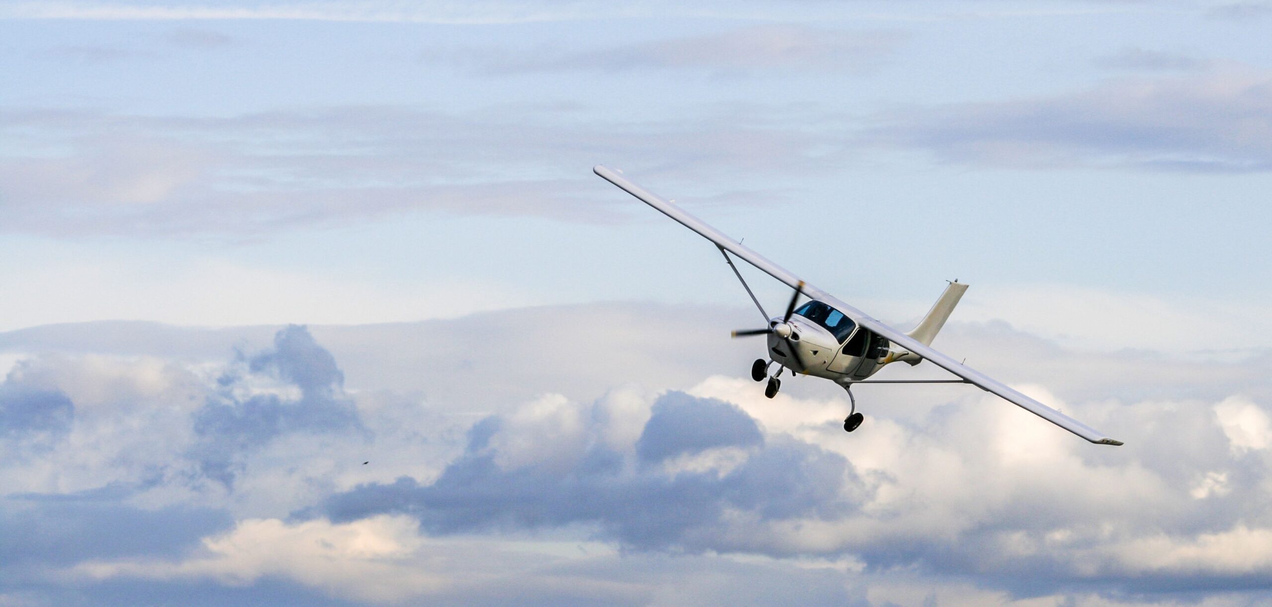 Propeller plane flying on the cloudy sky background