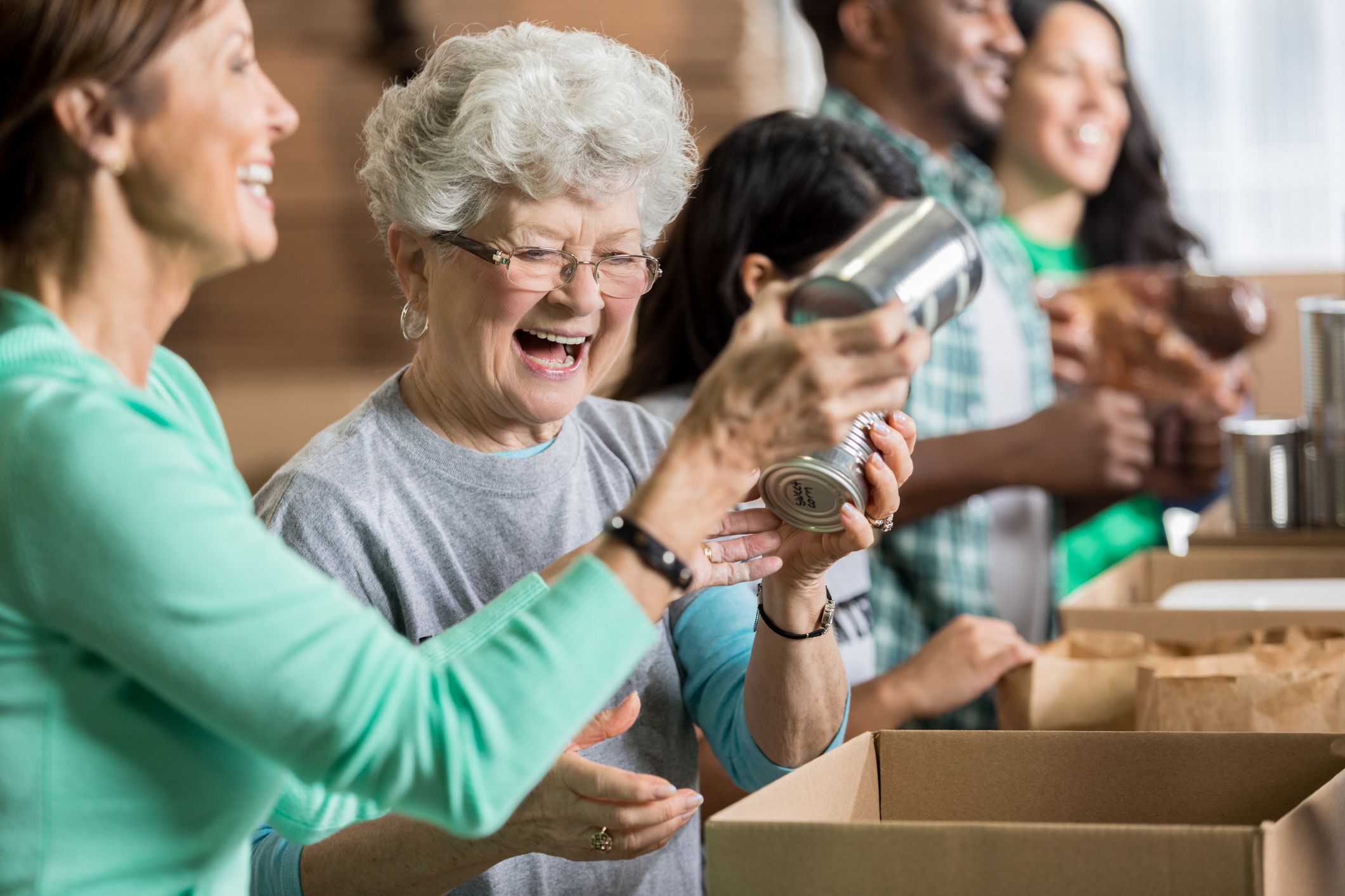 friends pack canned goods into boxes during community food drive. Volunteers