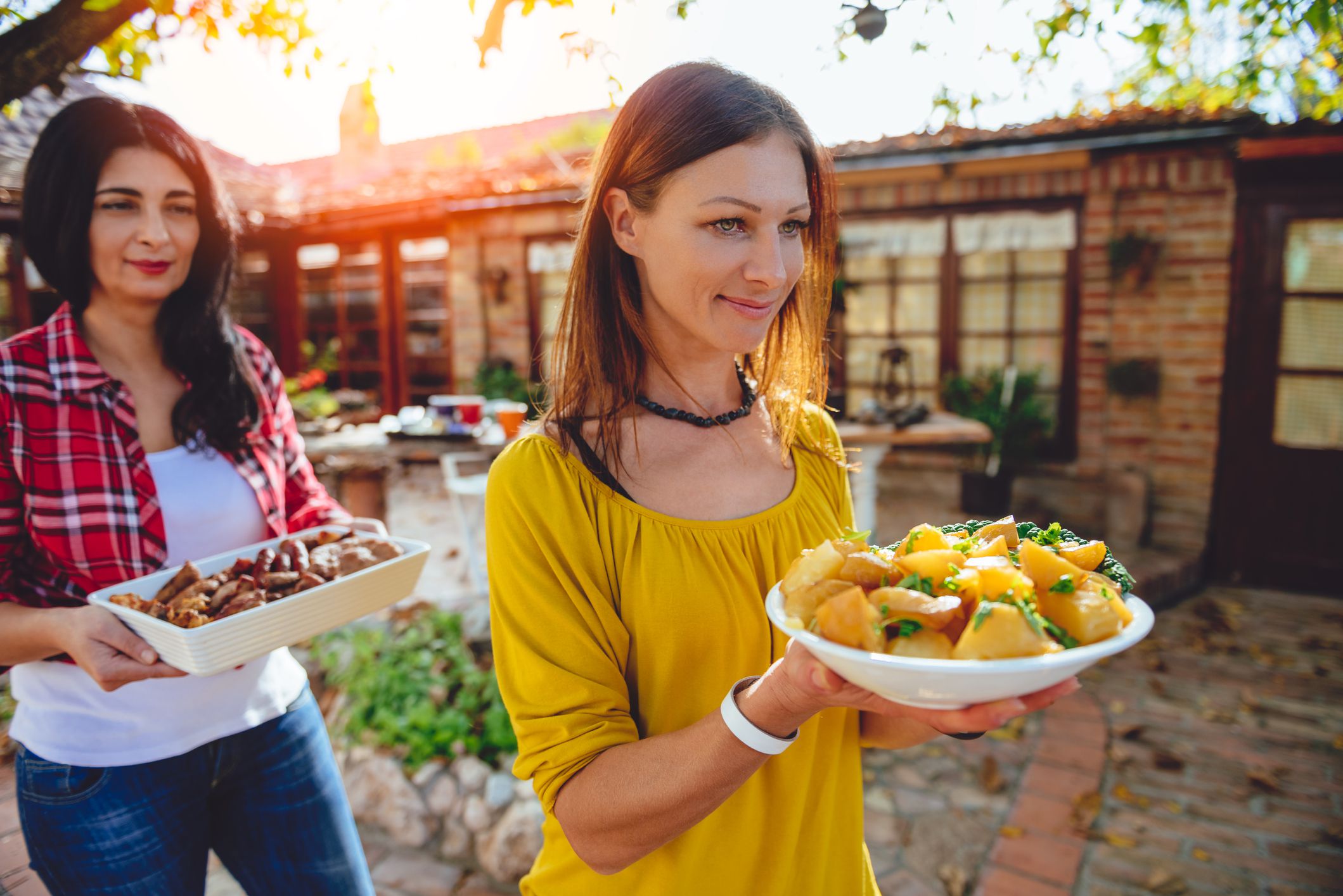 Woman carrying a bowl with roasted potatoes at backyard patio