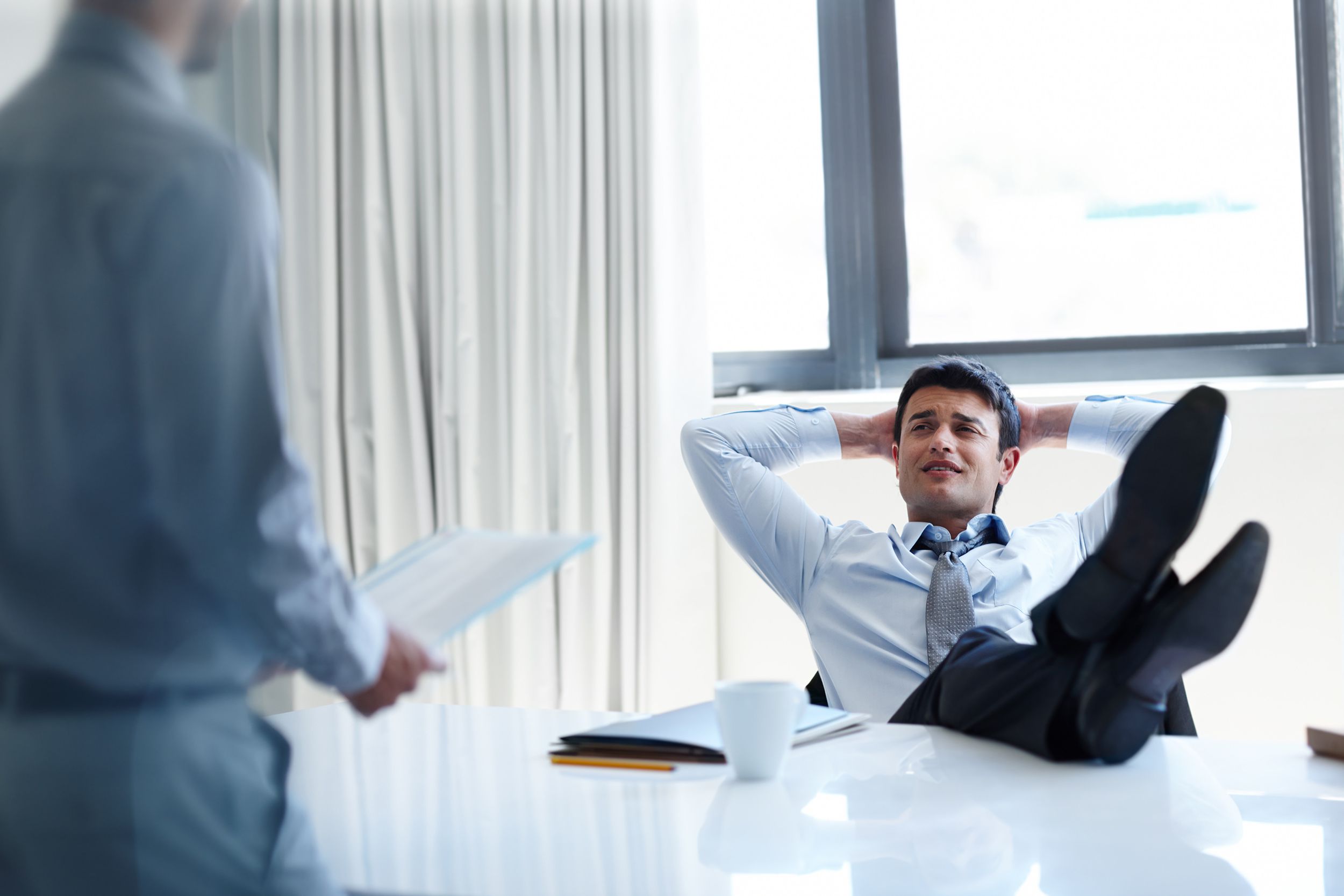 Indian man sitting at desk with feet on table and laying back