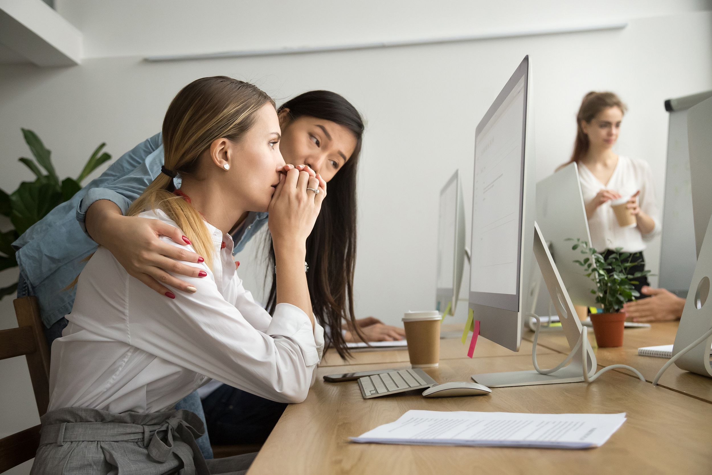Asian colleague supporting caucasian coworker reading bad news in email