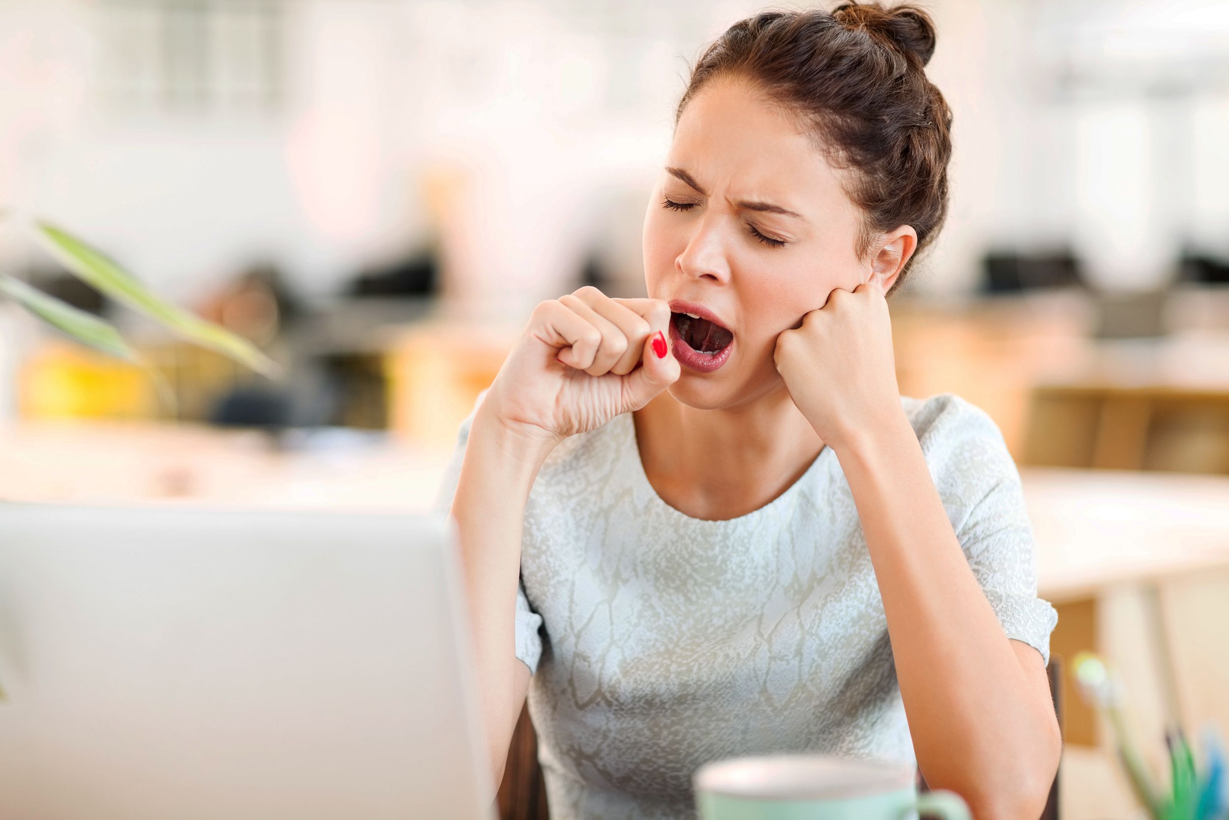 woman yawning while sitting at desk at work