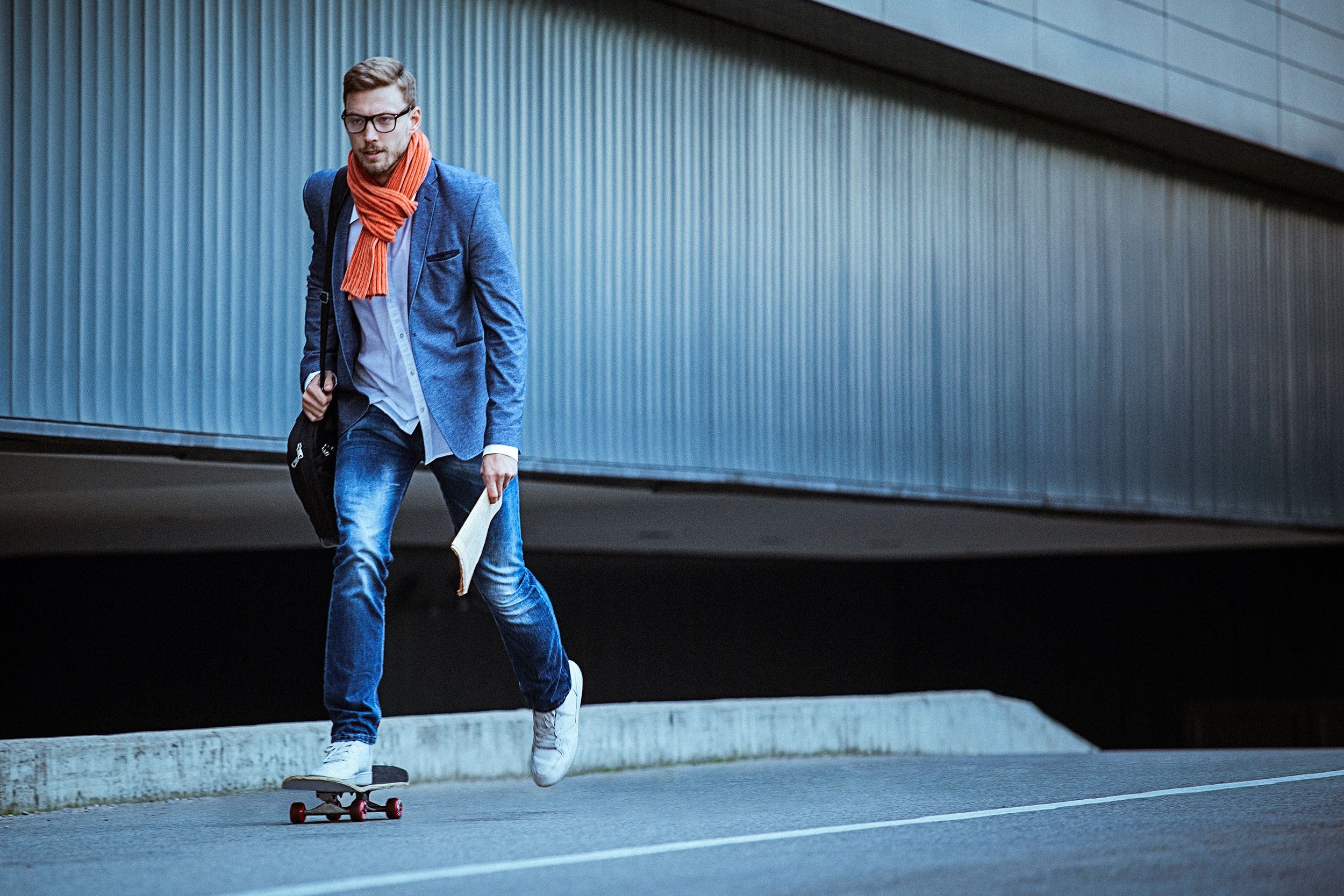 young casual businessman commuting to work skateboarding