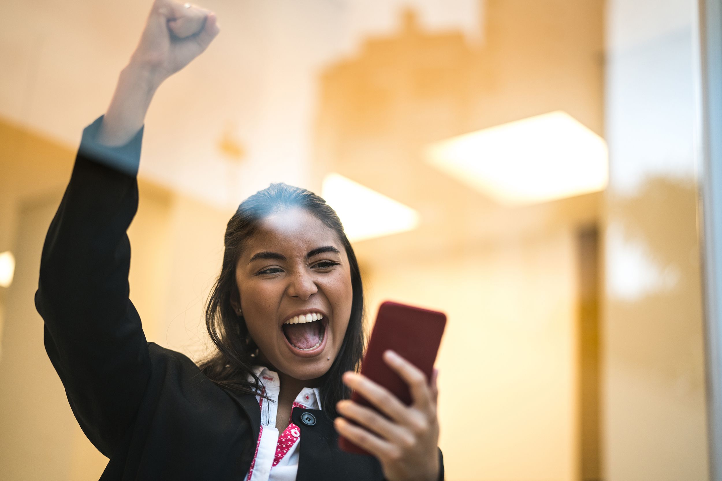 Asian business woman celebrating with mobile phone