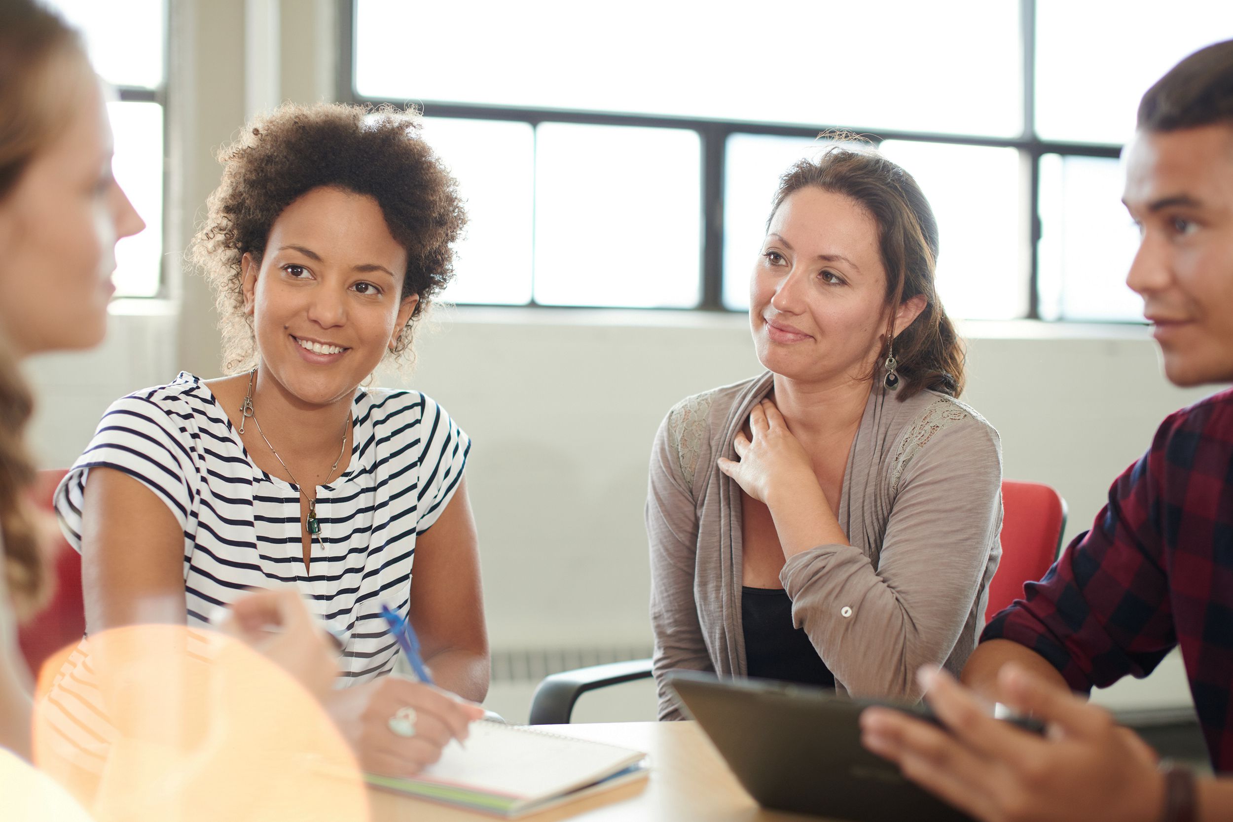 group of creative business entrepreneurs in an open concept office brainstorming together on a digital tablet