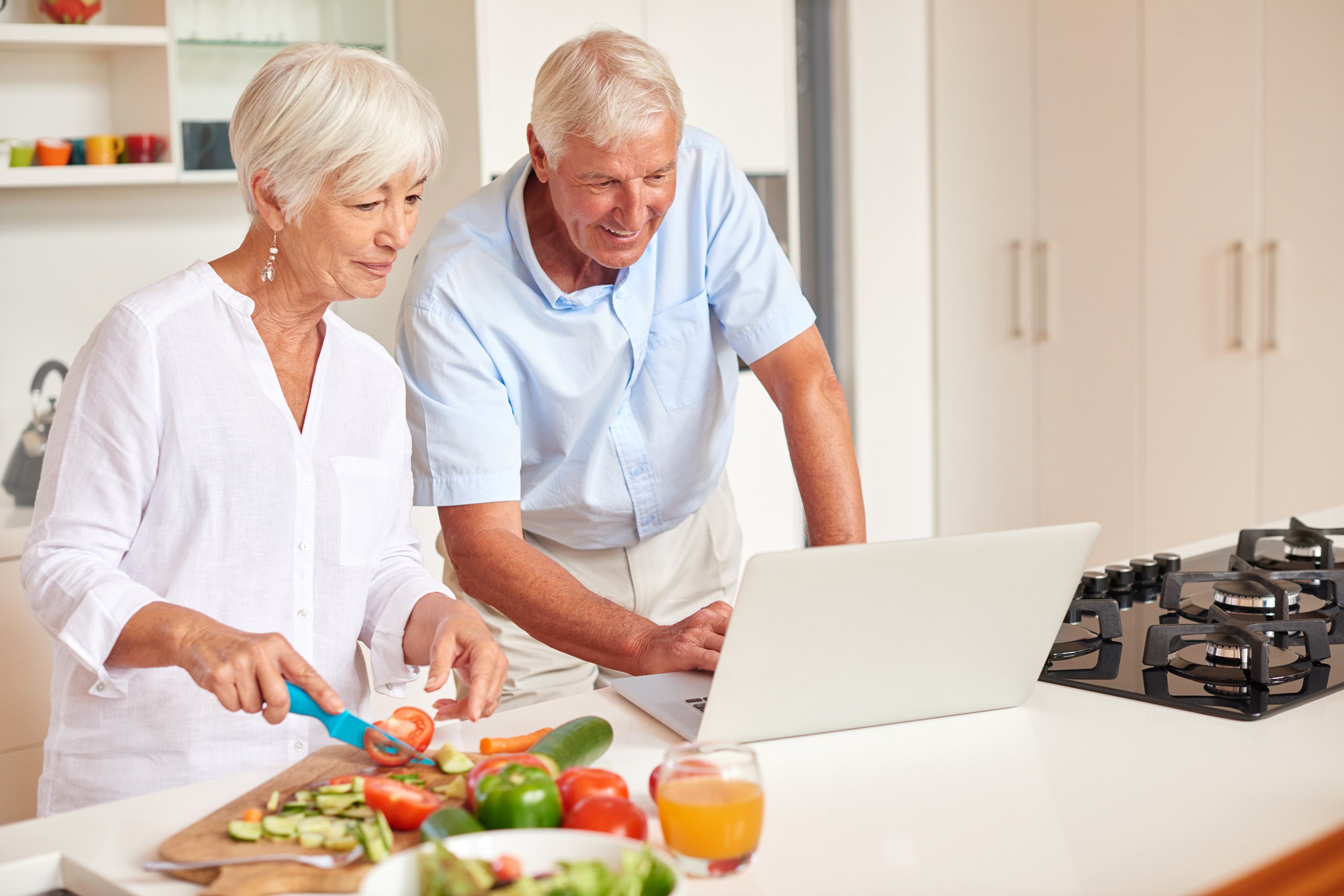 Senior couple cooking in the kitchen and following a recipe