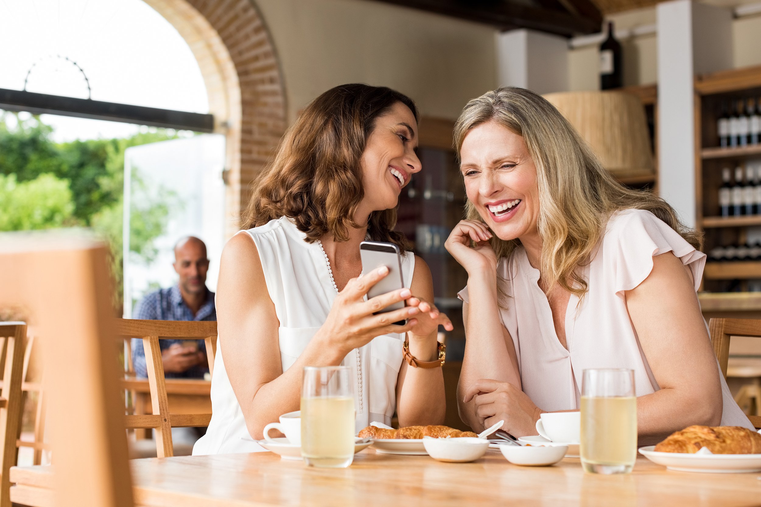 Two middle-aged women laughing and talking at a restaurant