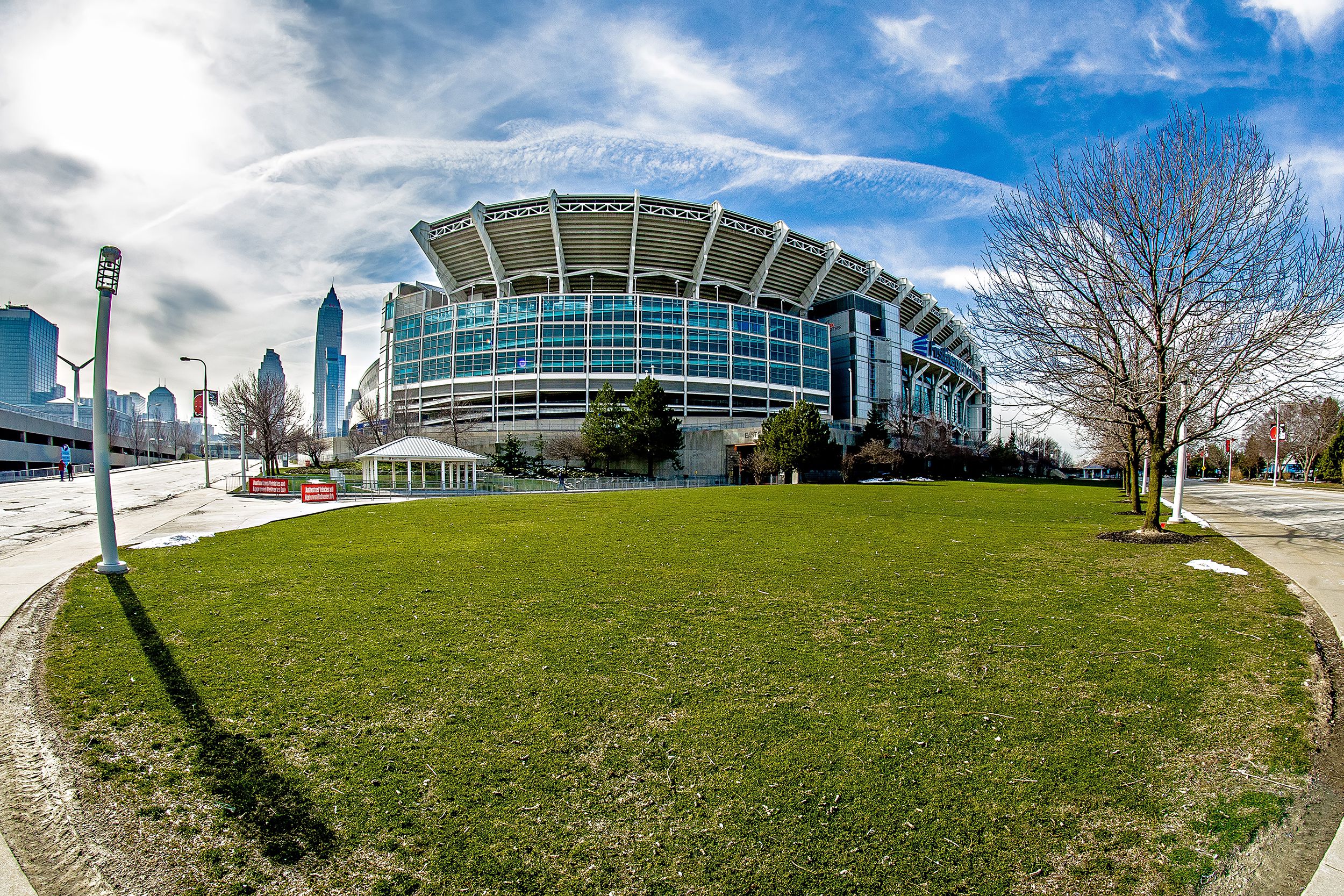Cleveland Browns, FirstEnergy Stadium, Cleveland, fisheye lens view of exterior with grass in the foreground and against a dramatic blue sky with the sun and white clouds, on a sunny winter day with city in the background