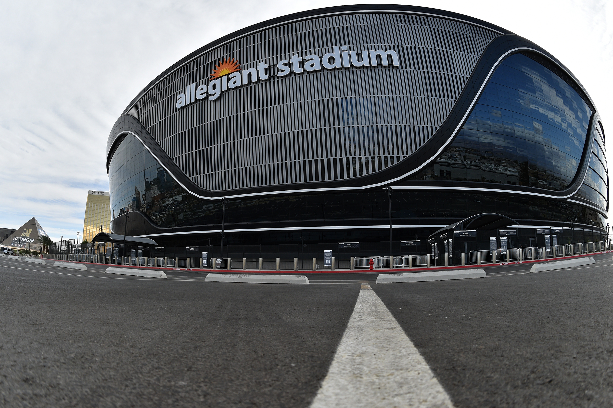 Las Vegas Raiders, Allegiant Stadium, Paradise, Nevada, dramatic fish-eye lens of front exterior, empty, with road in the foreground, stadium against a white cloud blue sky
