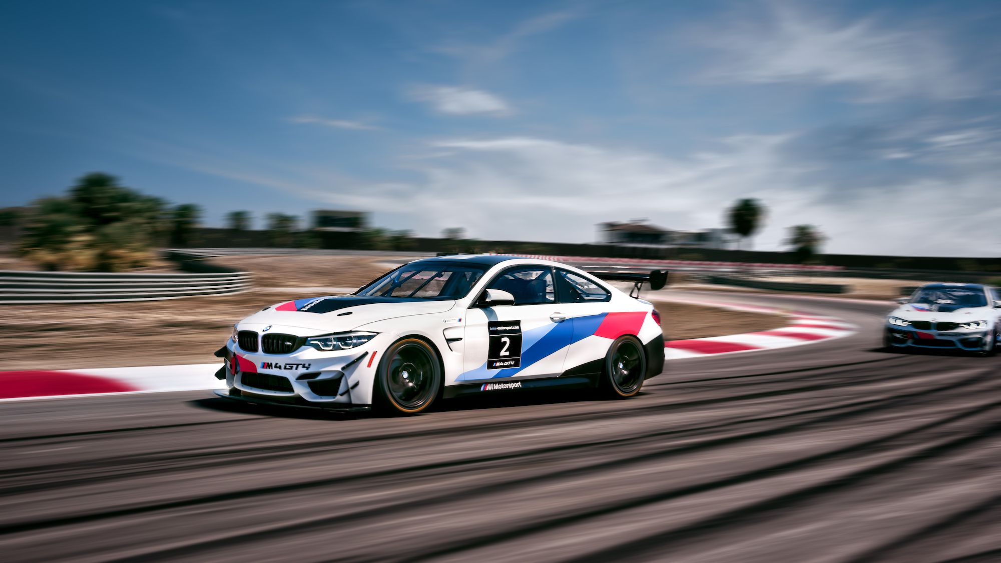 BMW M4 GT4 race car coming out of a corner on the track