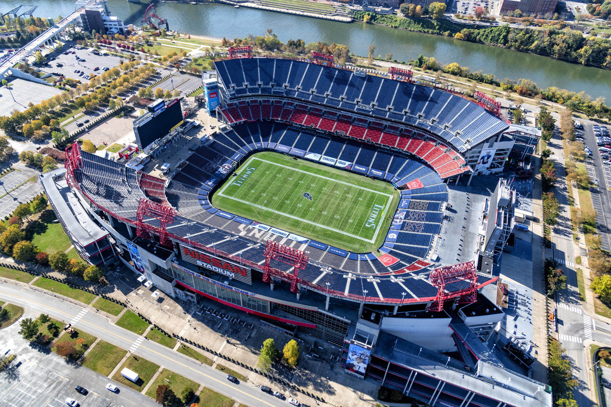Aerial of Tennessee Titans, Nissan Stadium, Nashville, empty field and seating, surrounded by parking with Cumberland River in the background, during late fall