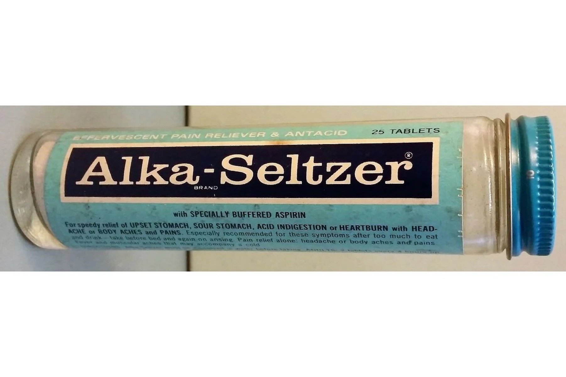 A vintage glass bottle labeled "Alka-Seltzer" with a blue and white label, containing 25 tablets—one of the first Walmart store items. The label describes it as an effervescent pain reliever and antacid for upset stomach.