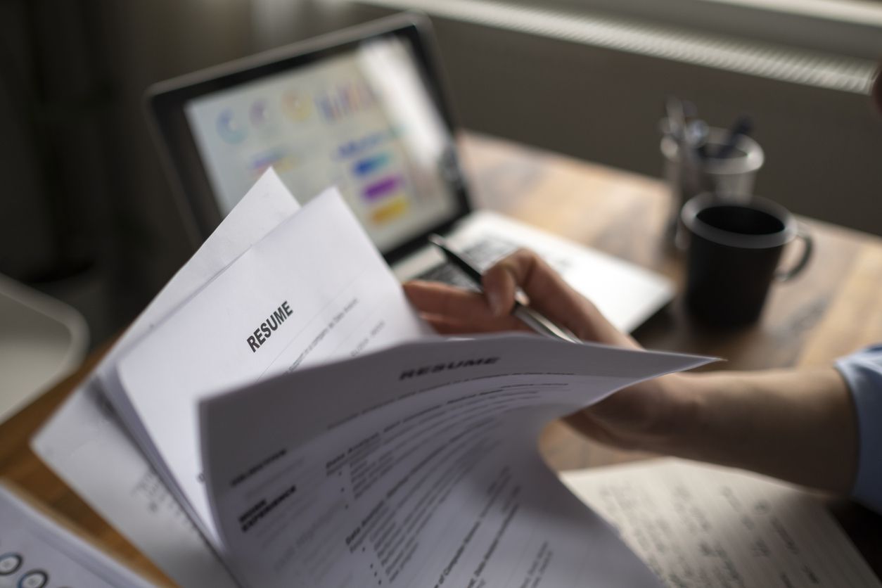 A job applicant reviewing their resume with their laptop opened up.