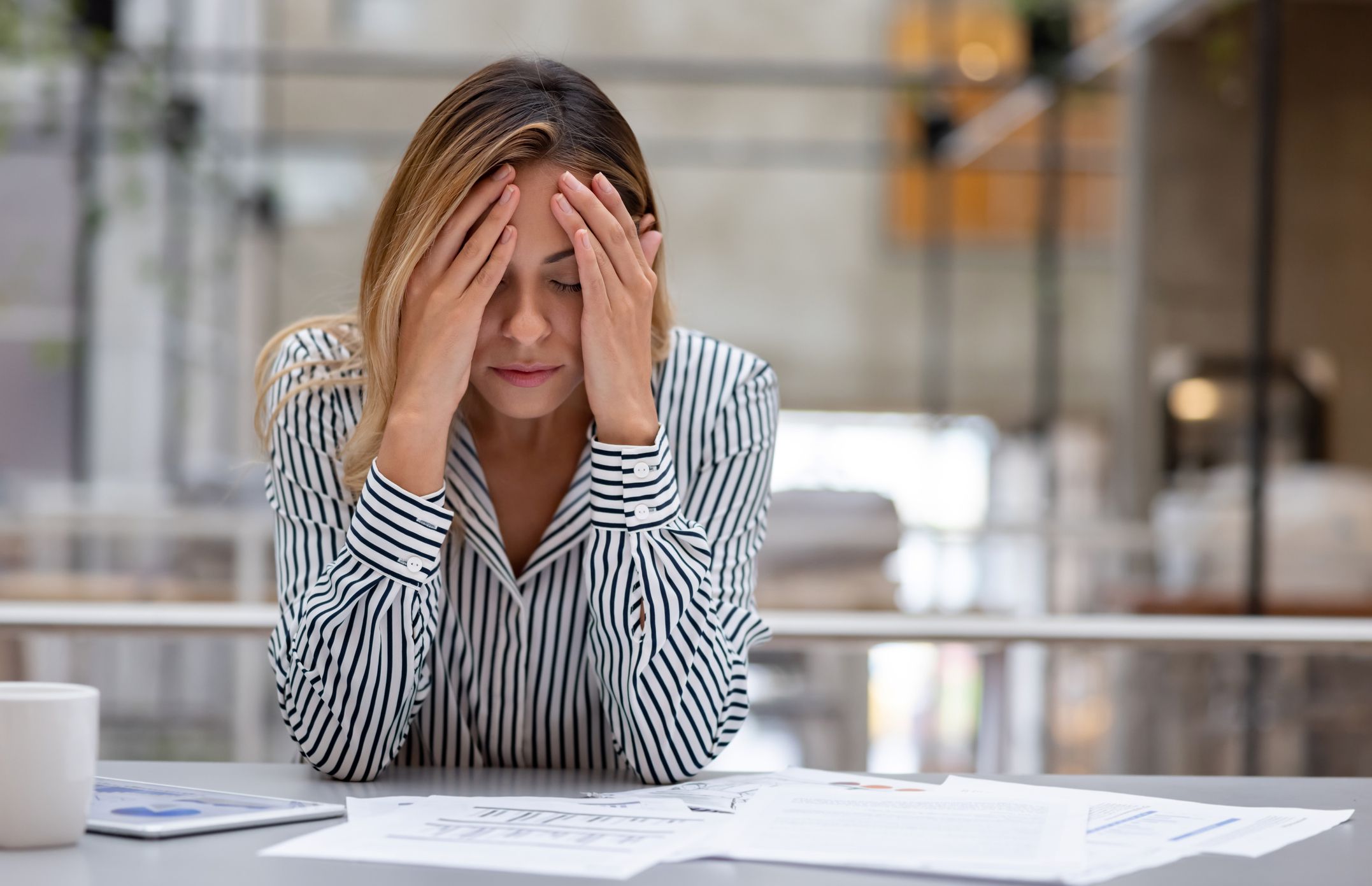 Stressed business woman having a headache at the office and looking very worried. **DESIGN ON ALL DOCUMENTS BELONG TO US**
