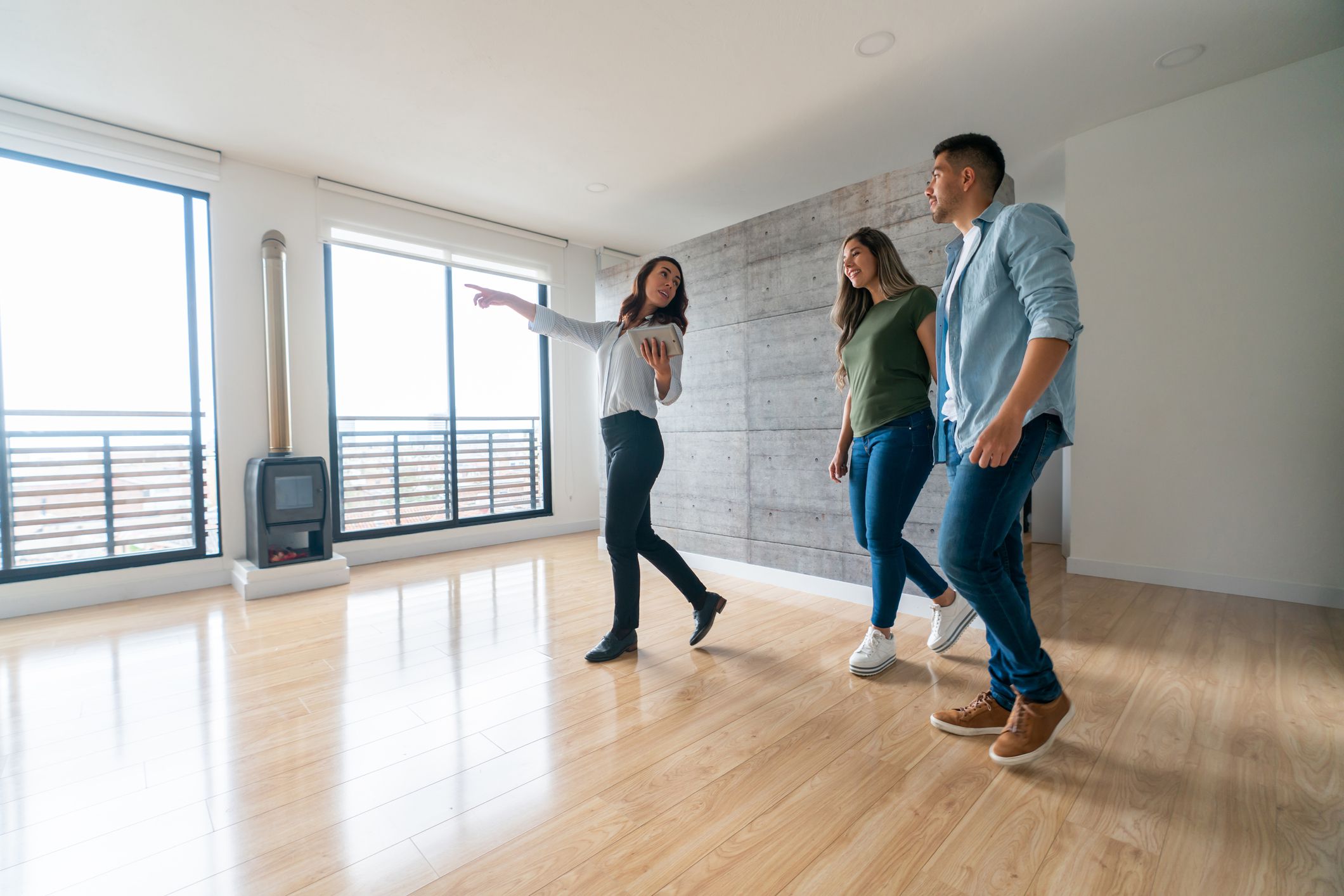 Real estate agent showing a house for sale to a happy couple - home ownership concepts