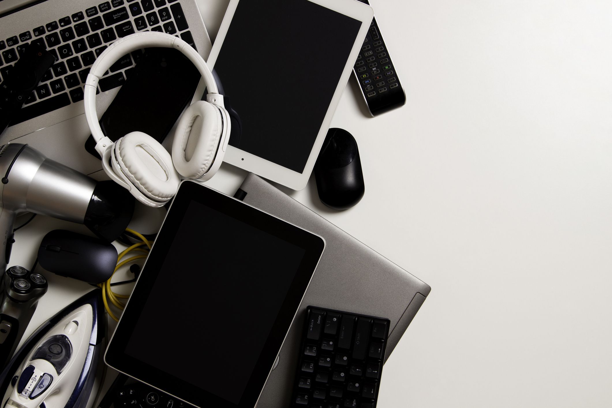 Old computers, digital tablets, mobile phones, many used electronic gadgets devices, cords, broken household and appliances on white background. Planned obsolescence, electronic waste for recycling