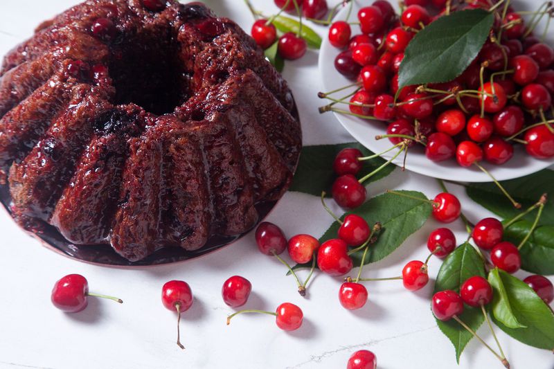 Chocolate cake with sweet cherry on white background.