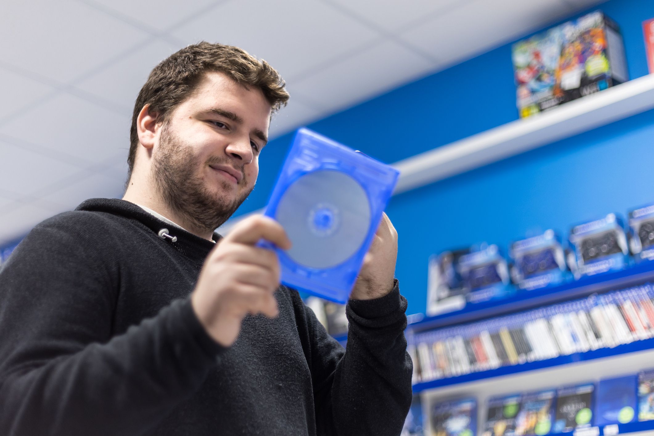 Profile of a handsome young guy browsing the gaming section at a local store