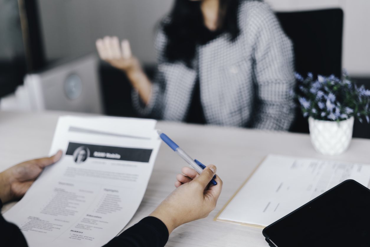 A job interviewer reviewing a printed out resume with their pen.