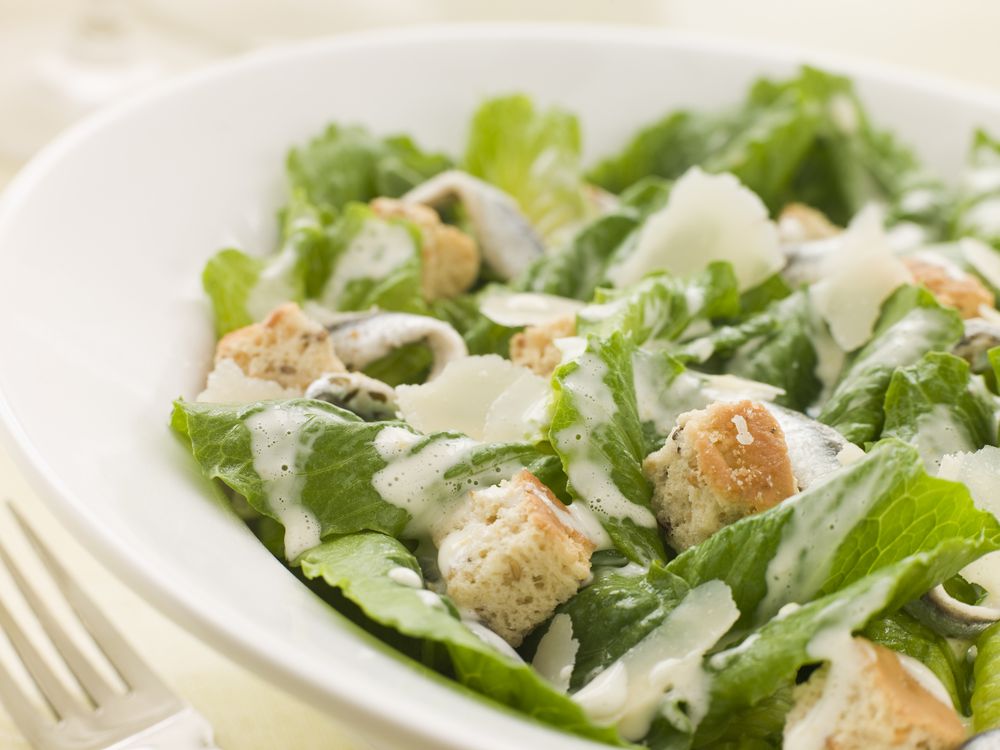 A Caesar salad in a white ceramic bowl