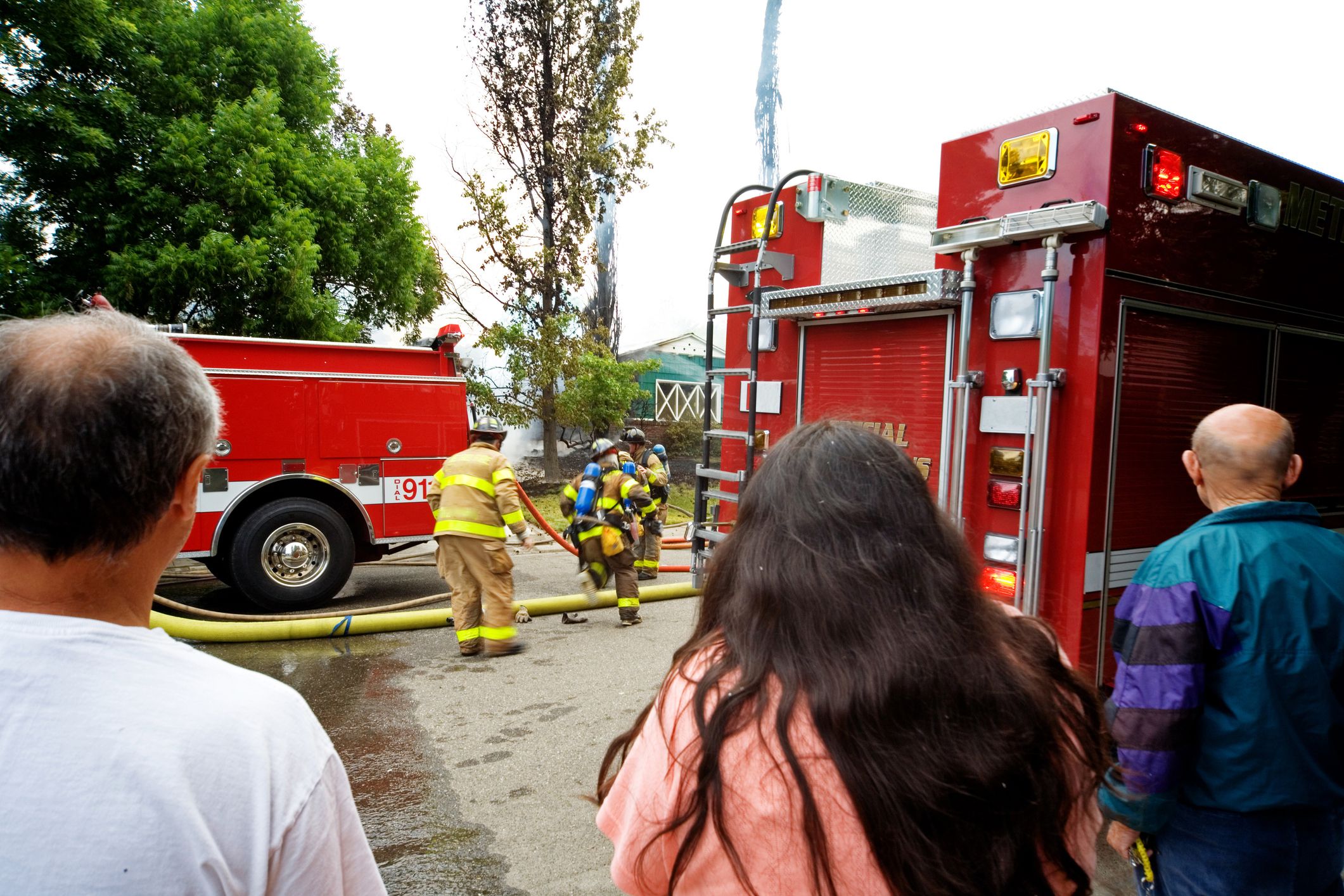 people observing firefighters on residential street