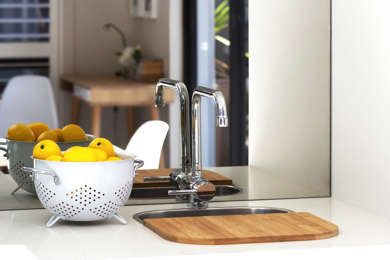 An image of a mirror behind a kitchen sink.