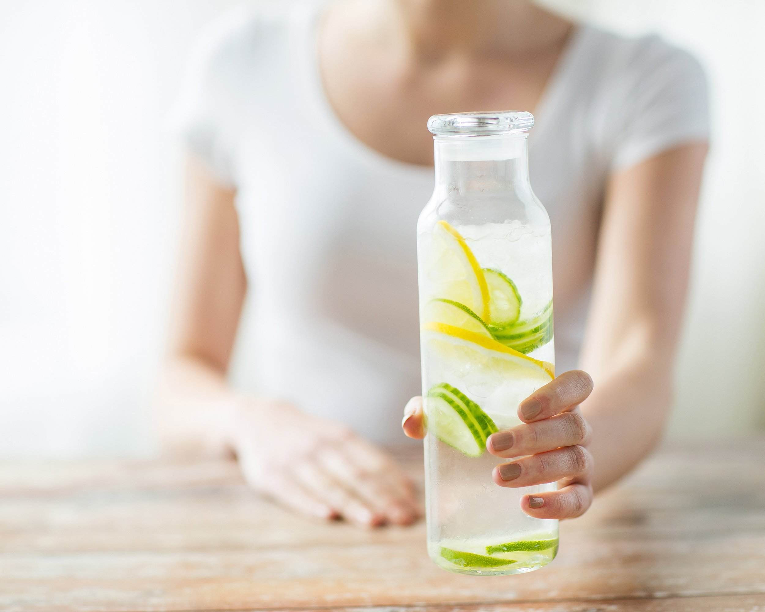 close up of woman with fruit water in glass bottle