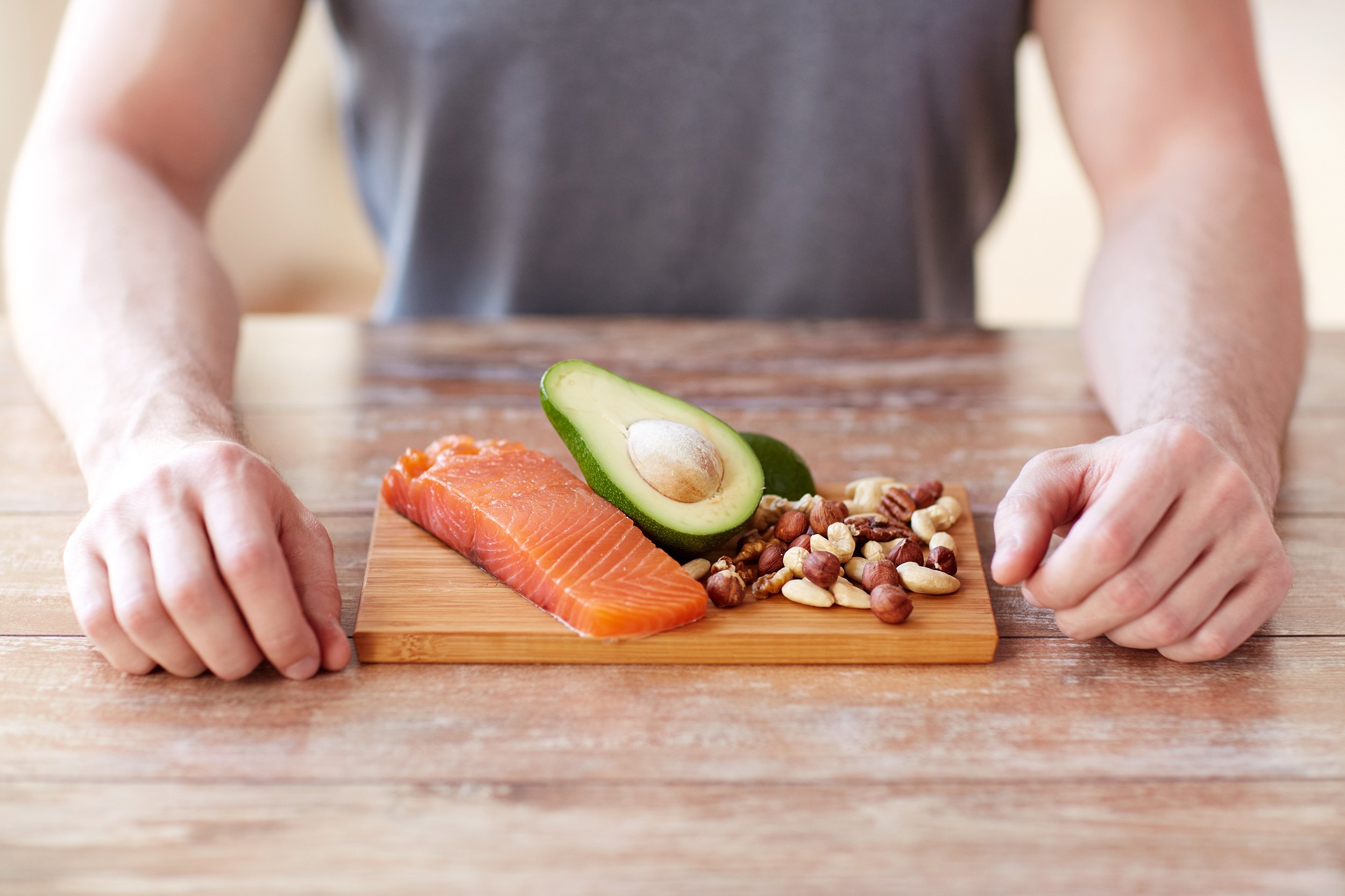 close up of male hands with food rich in protein on cutting board on table
