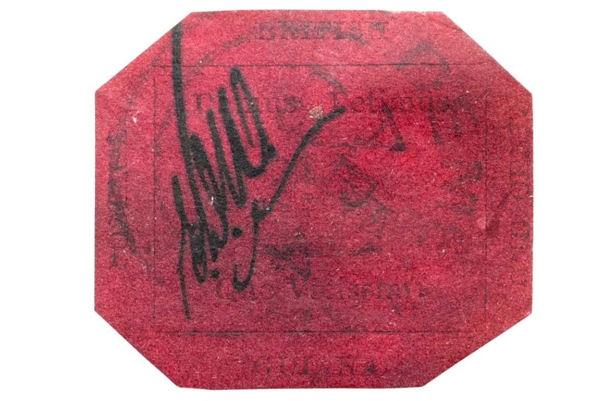 A rare, red octagonal postage stamp with faded text and a bold black signature across the front, set against a white background—an exceptional find for lovers of expensive collectibles.