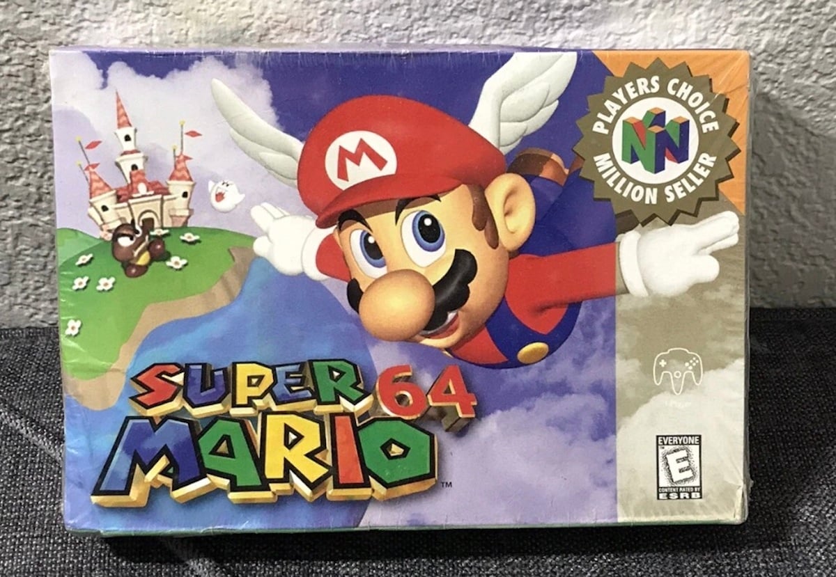 The image shows the box art for the Nintendo 64 game "Super Mario 64," an iconic title that has become one of the most expensive collectibles, featuring Mario flying with a winged cap near Princess Peach’s castle.