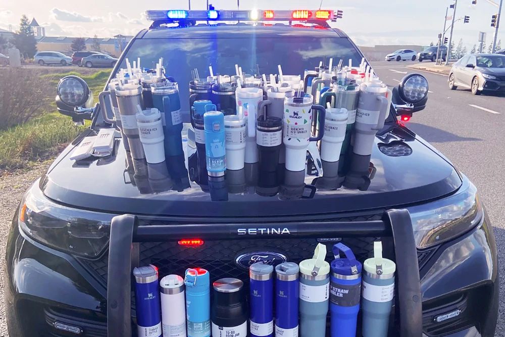 Around 60-70 Stanley cup products are pictured on the front of a Ford Setina. They had been stolen by a 23-year-old woman who was charged with grand theft after she was pulled over with the cups in her car.