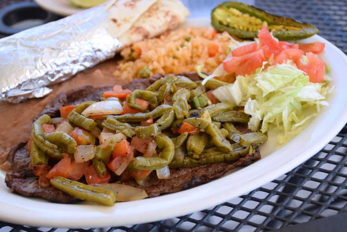 Closeup of Asada Entera con Nopales Plate, El Milagrito Cafe, San Antonio, on an outside black metal table on a patio at the restaurant