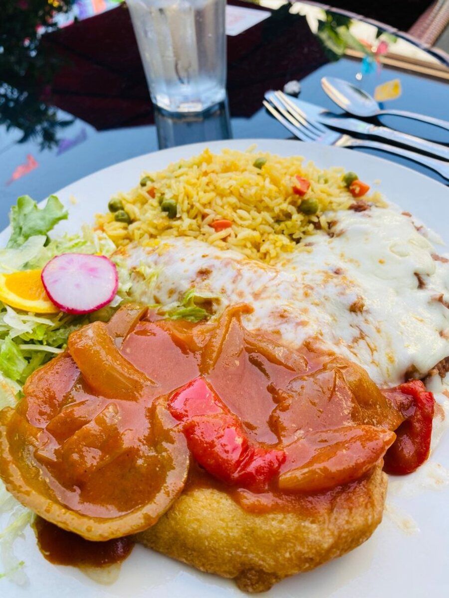 Chile Relleno, Chicken Enchilada, Refried Beans with Melted Cheese, and Rice on a white plate, Don Antonio’s, Los Angeles, selective focus, on a mirrored black table with utensils and a glass of water, outside on the patio at the restaurant