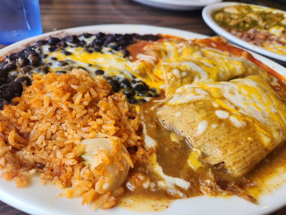 Closeup of Combo Plate with chilled relleno, pork tamales and beef enchilada with rice and black beans, Juan’s Place, Berkeley, California, another dish on the top right, on a table at the restaurant