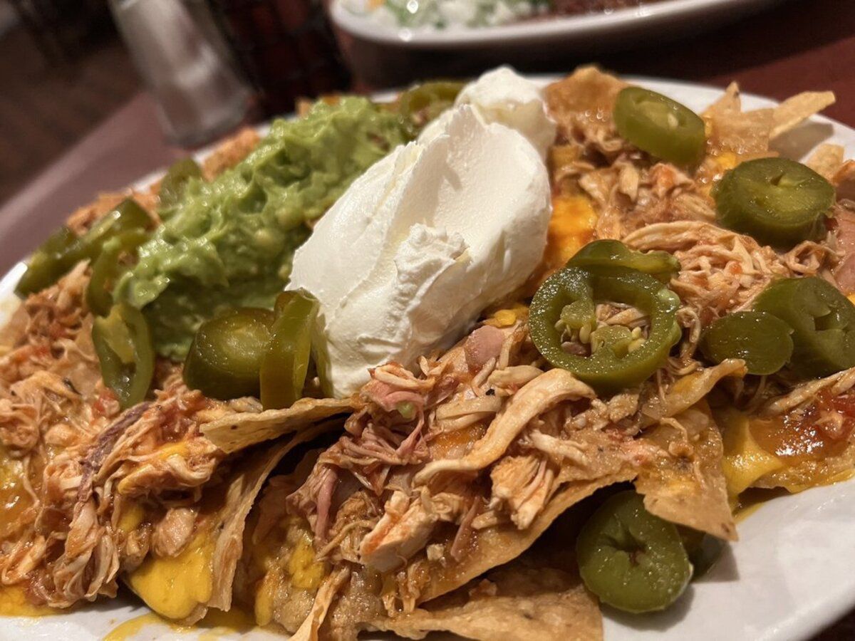 Closeup of Nachos Grande on a White Plate, La Cabaña, Los Angeles, Selective Focus, with another plate on a wooden table blurred in the background