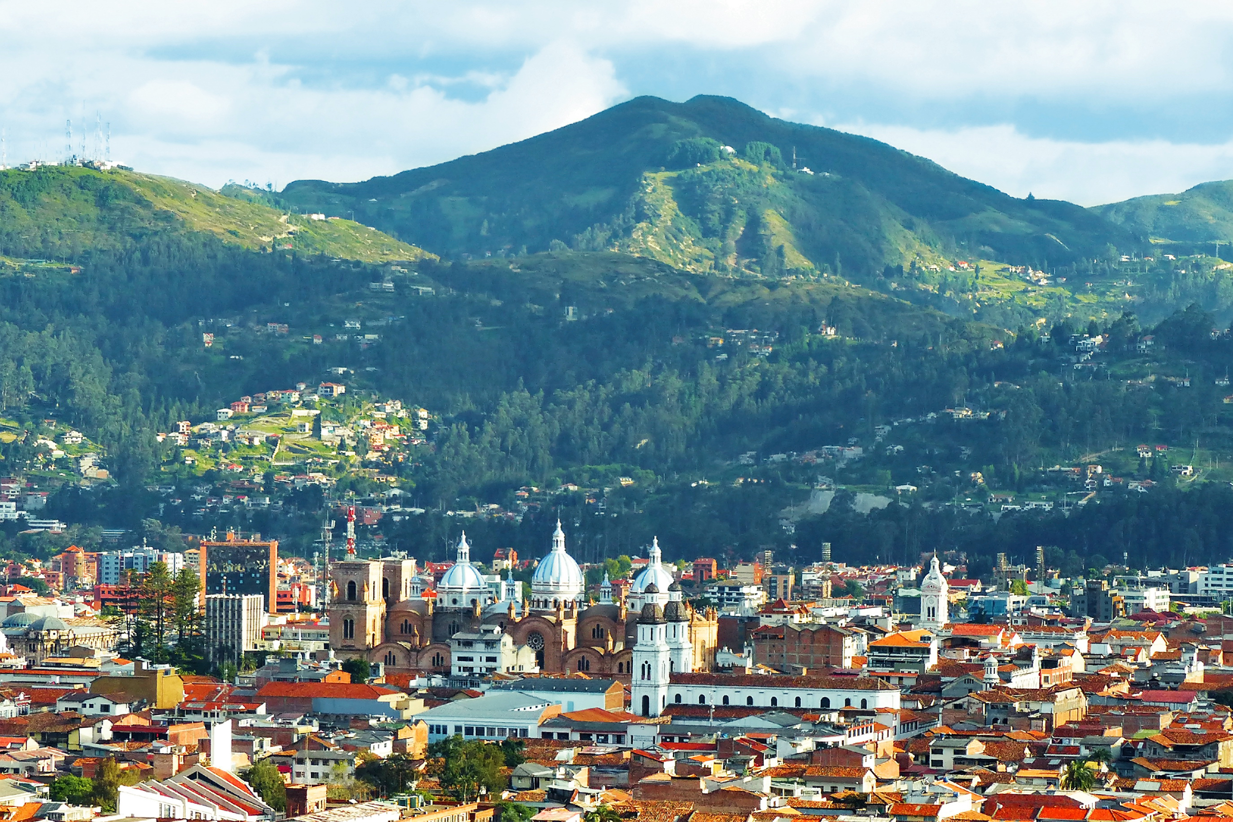 Cuenca, Ecuador, panoramic view of the city with mountains in the background, white clouds and blue sky in on the top