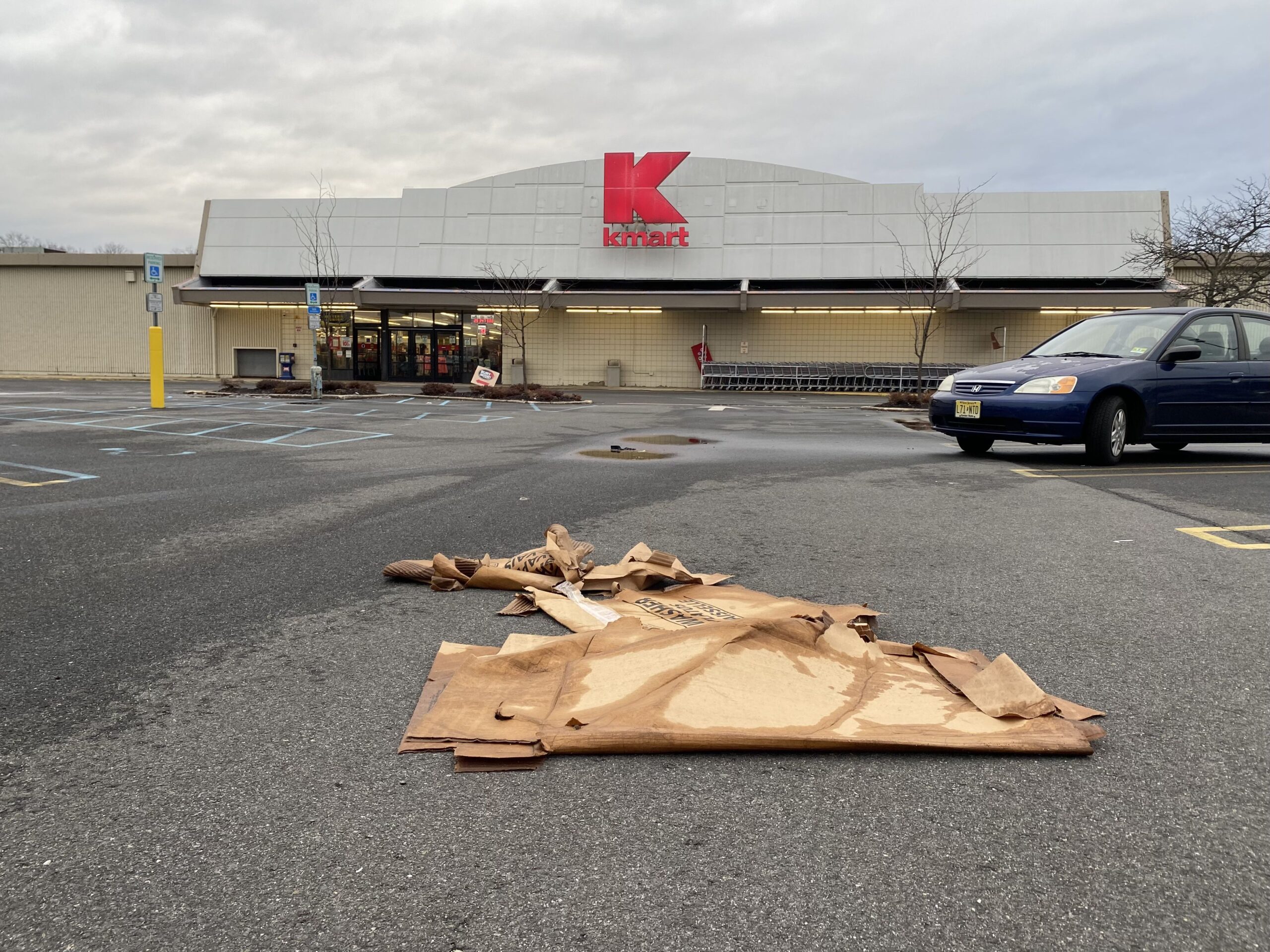 Flattened wet cardboard in a mostly empty parking lot of a Kmart