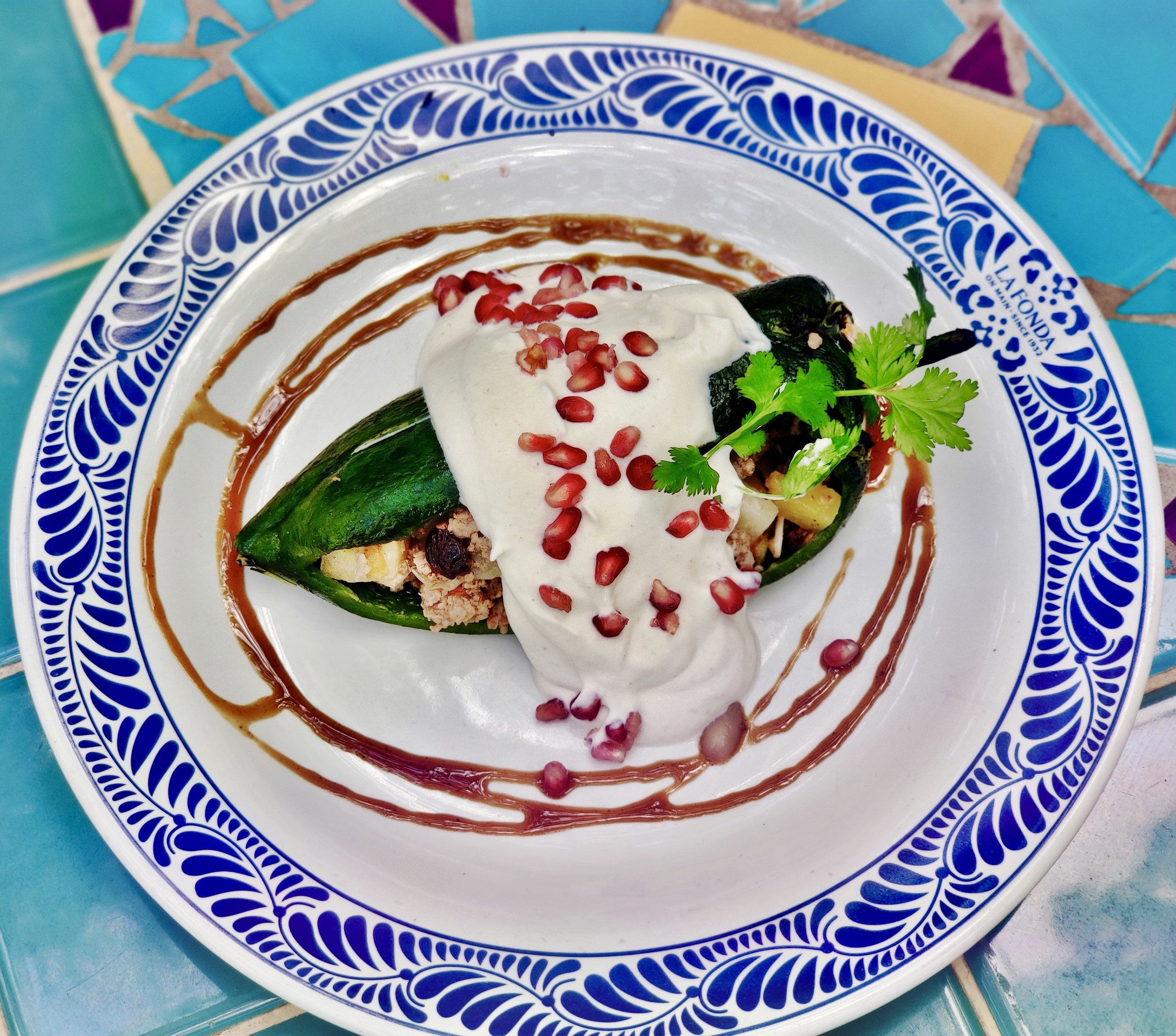 Mexican Dish on a white plate with a blue design, La Fonda on Main, San Antonio, on an artsy blue-green tiled table on the patio of the restaurant