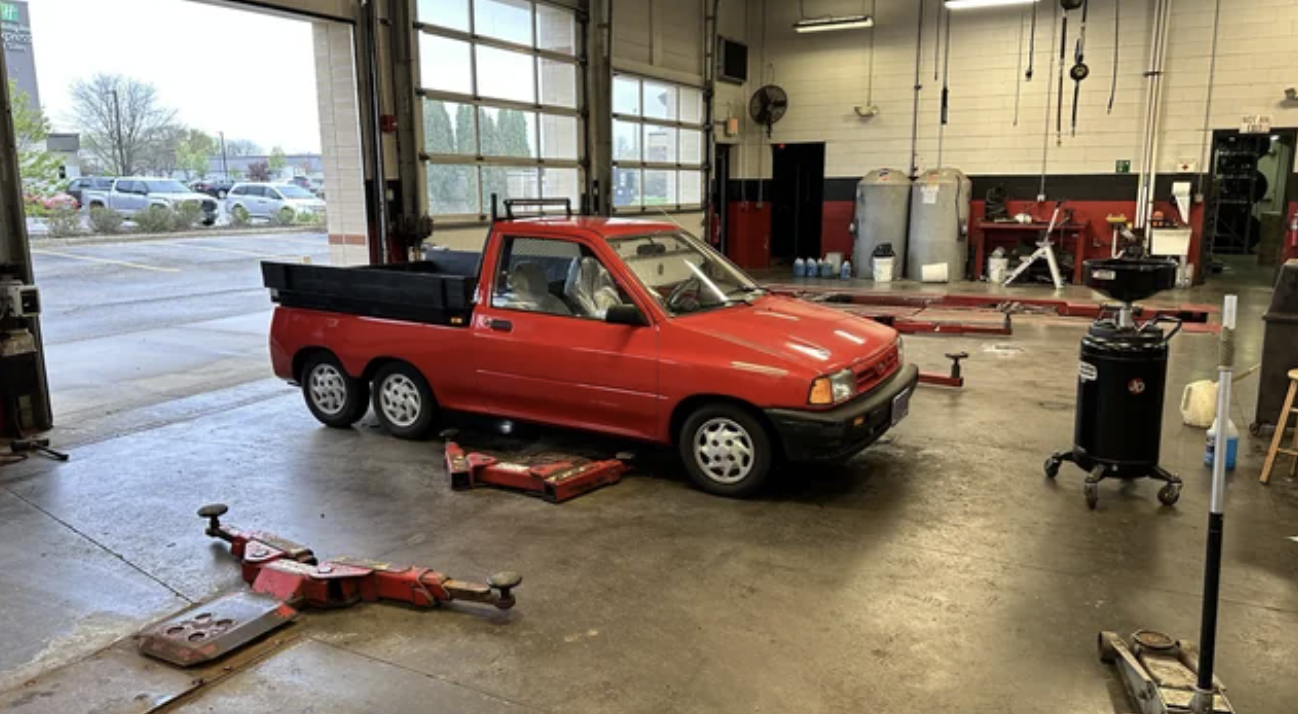 An image of a red-colored, 6-wheeled Ford Festiva.